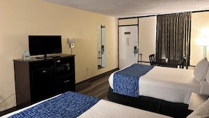 A hotel room with two beds, a television on a dresser, a mirror, and a door with a security camera. - Travelodge by Wyndham Clarksville (Clarksville)