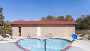 A swimming pool with a heart-shaped design, surrounded by lounge chairs and a building with a red roof. - Travelodge by Wyndham Clarksville (Clarksville)