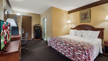 A hotel room with a bed, a television, a desk, and a door.
