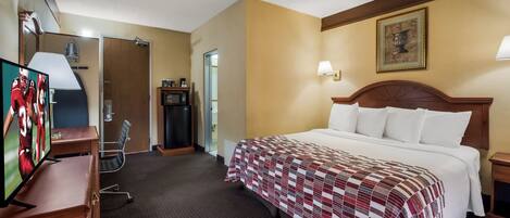 Una habitación de hotel con cama, televisor, escritorio y puerta.
