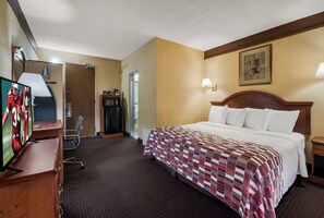 A hotel room with a bed, a television, a desk, and a door. - Red Roof Inn & Suites Newark - University (Newark)