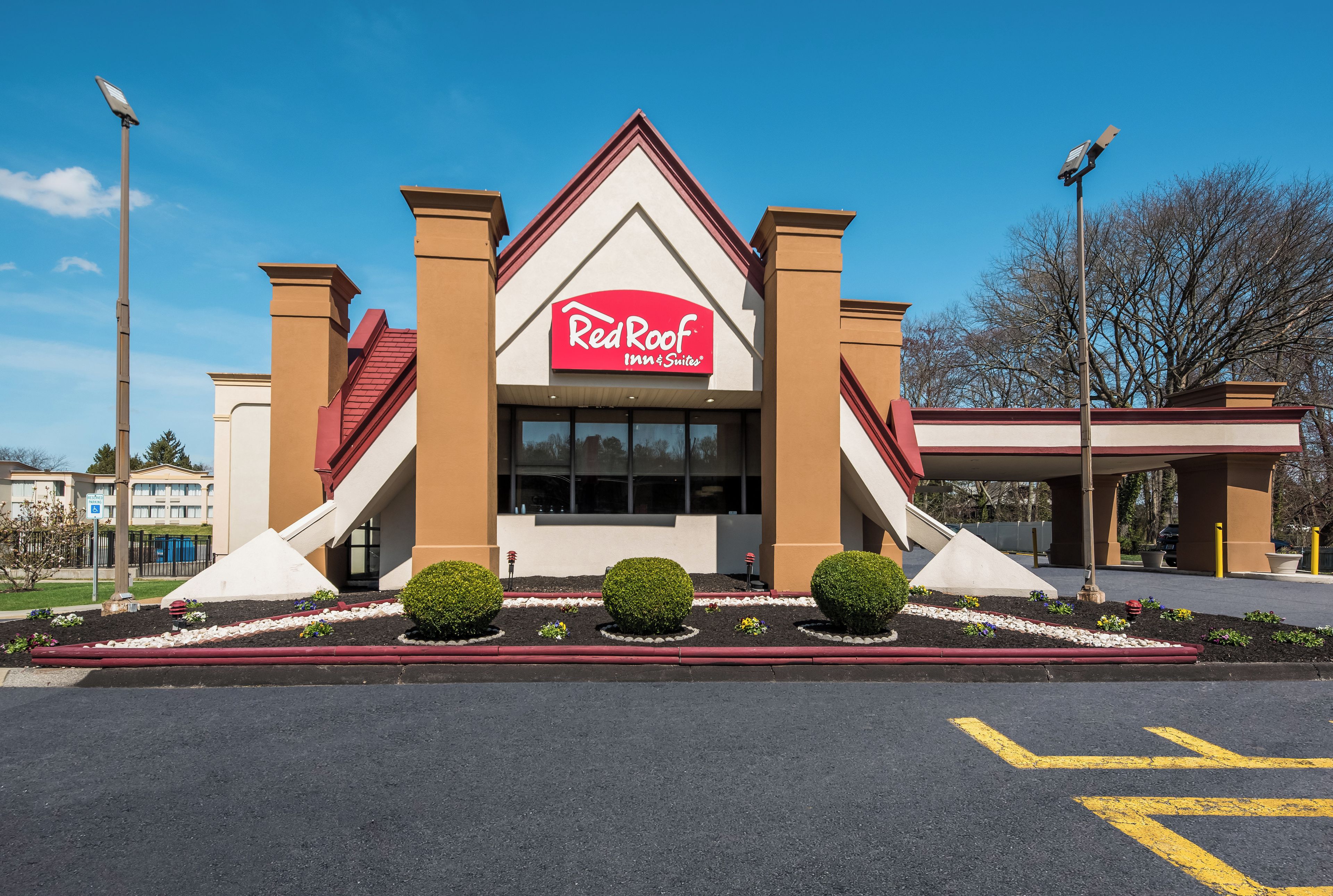 Et Red Roof Inn & Suites hotel med et markant trekantet tag og en parkeringsplads foran.