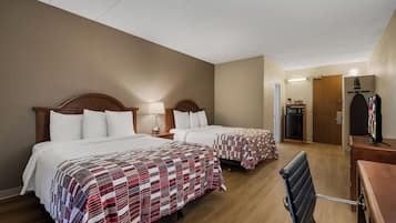 Habitación de hotel con dos camas, un escritorio, una silla, un armario y un televisor.