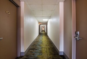 Pasillo de hotel con piso alfombrado, puertas a ambos lados y un cartel que indica la habitación 180.