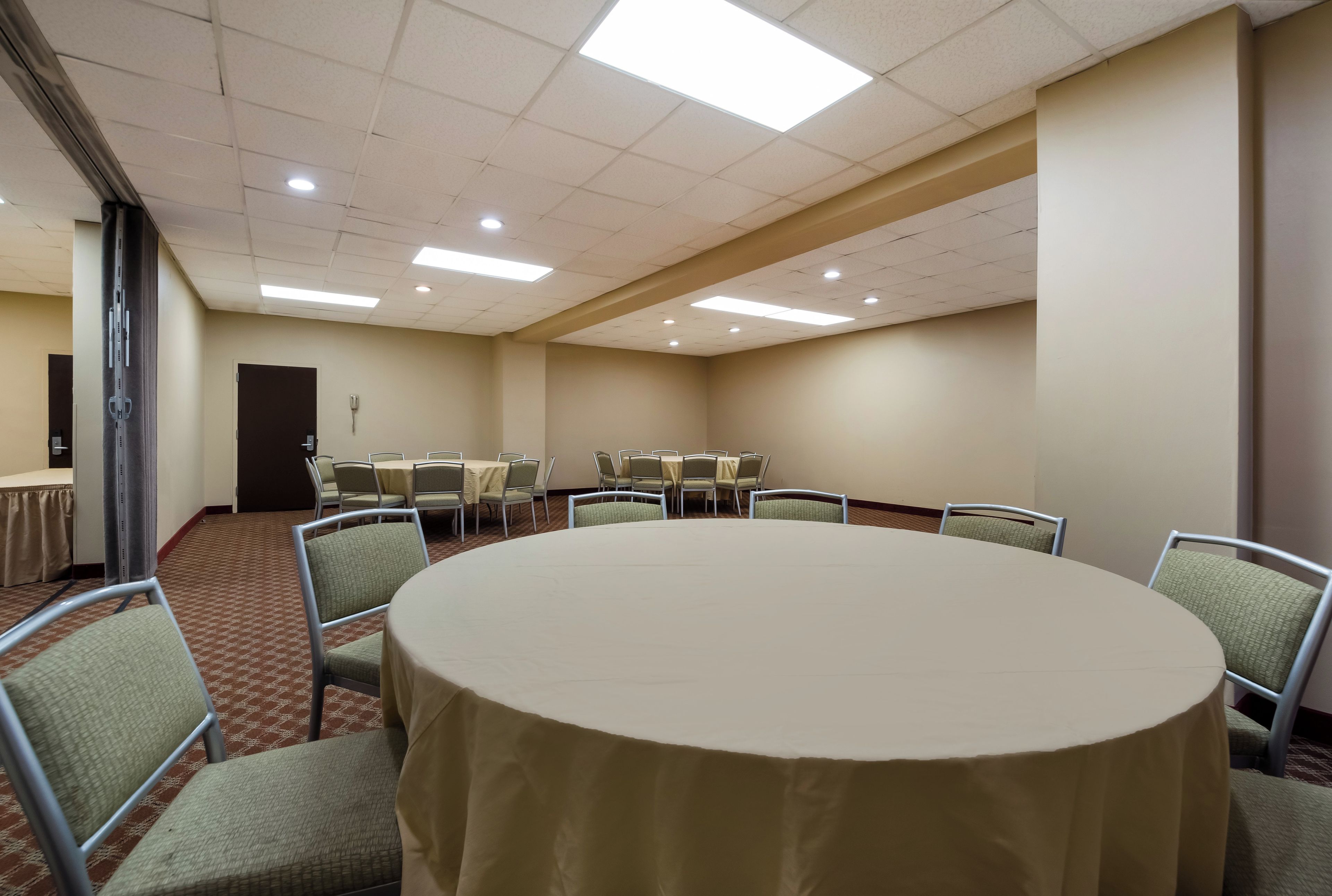 Una sala de conferencias con una mesa redonda, sillas y una puerta.