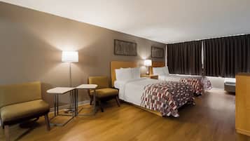 A hotel room with two beds, a sofa, a small table, and a lamp.