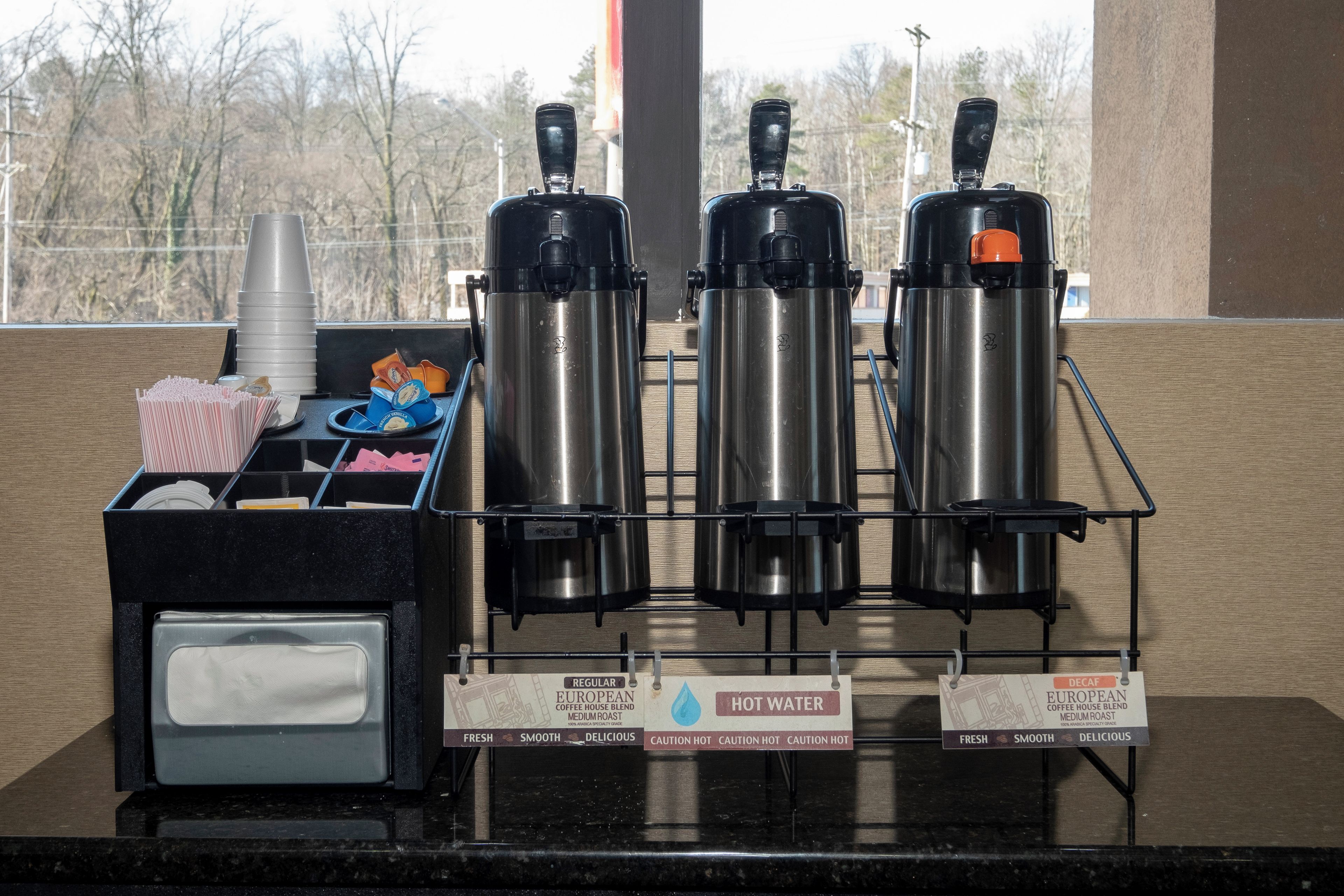 A coffee station with three coffee dispensers, a water dispenser, and a coffee machine.