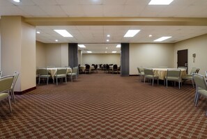 A conference room with tables and chairs, carpeted floor, and a plain wall with a door. - Red Roof Inn & Suites Newark - University (Newark)