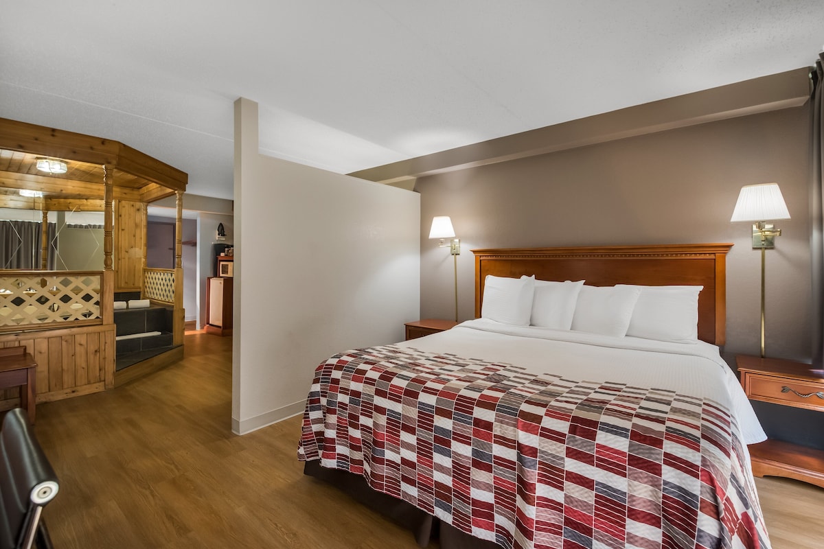 Habitación de hotel con cabecera de madera, colcha acolchada, dos lámparas de noche y un escritorio de madera con una silla.