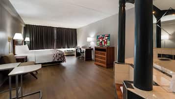 Une chambre d’hôtel comprenant un lit, un bureau, une chaise, une télévision et une salle de bain avec baignoire.
