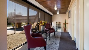 A covered outdoor area with a table and chairs, a potted plant, and a view of the outside. - Red Roof Inn & Suites Newark - University (Newark)