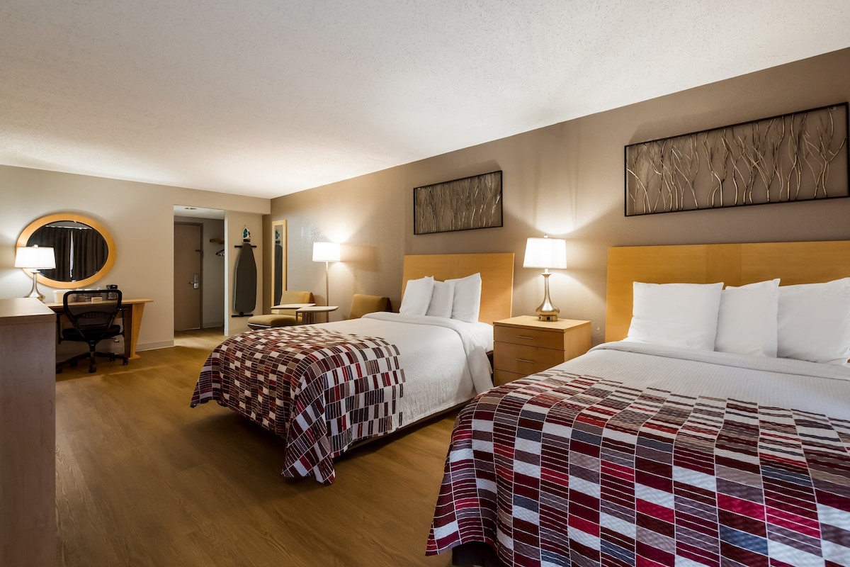 Una habitación de hotel con dos camas, un escritorio y una silla.