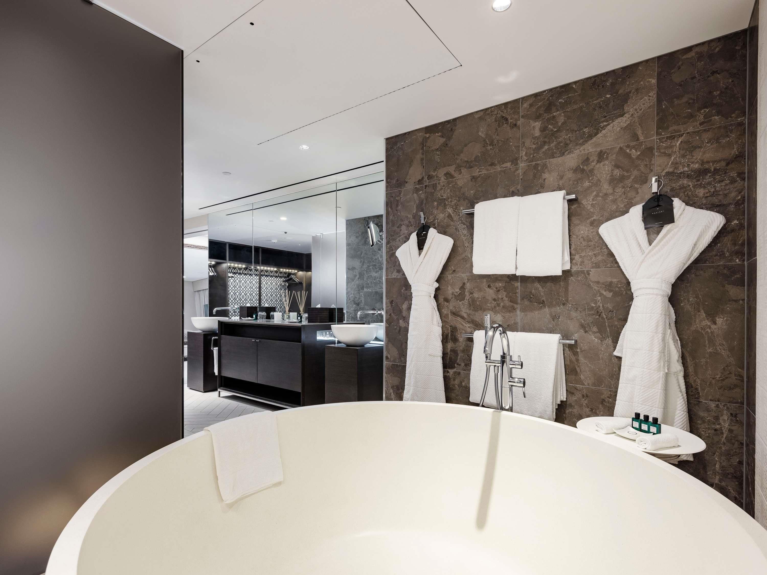 A modern bathroom with a freestanding bathtub, a large mirror, and a vanity with two sinks.
