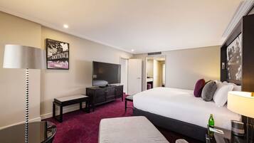 A hotel room with a bed, a desk, a chair, a TV, and a mirror.