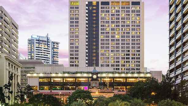 Un hotel de gran altura con varios pisos, una destacada torre de reloj y una fachada bien iluminada.