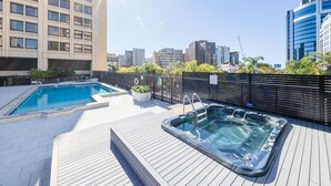 Una piscina al aire libre, sombrillas, sillones reclinables de piscina