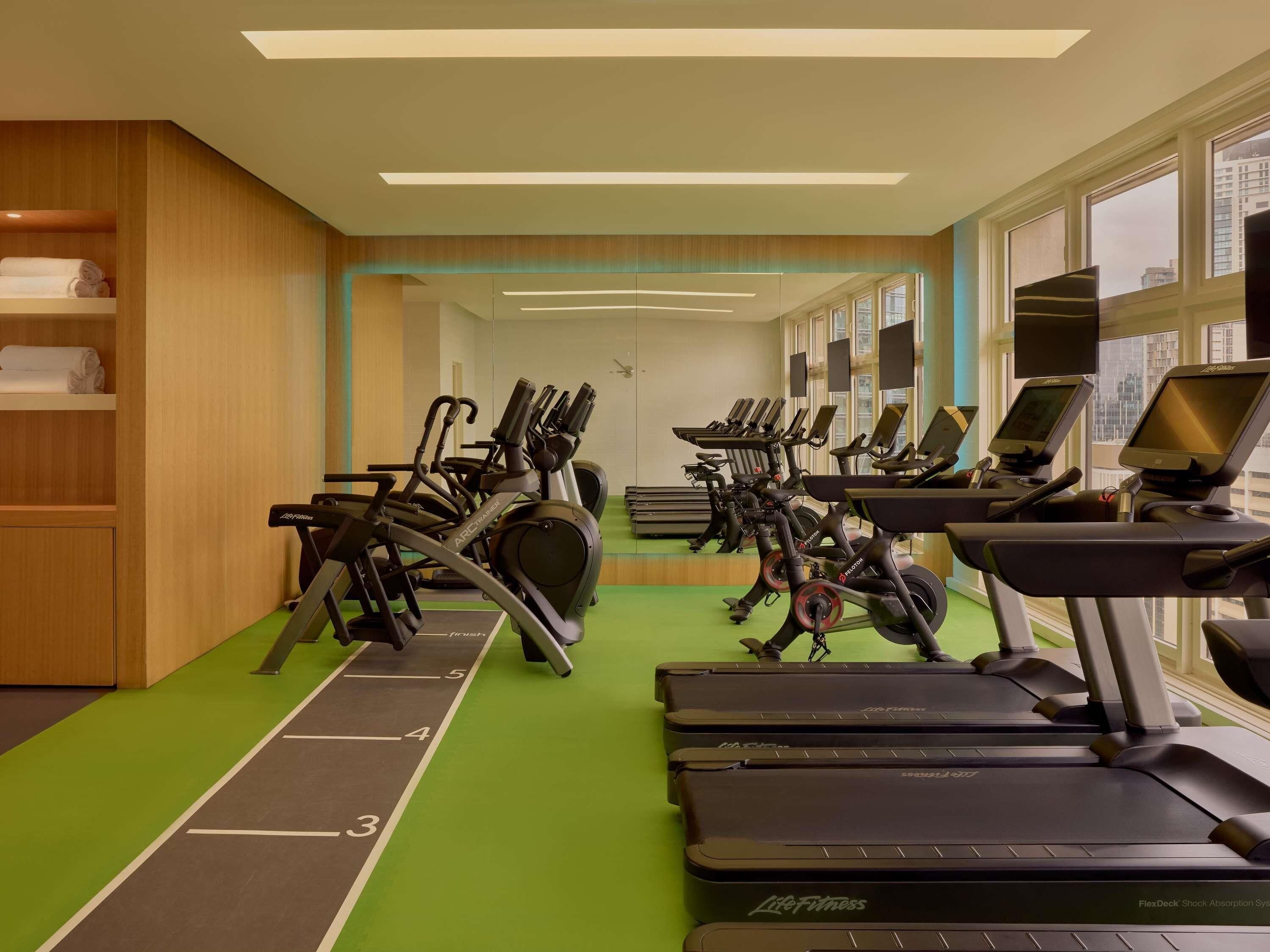 Un gimnasio con cintas de correr, elípticas y una pista de atletismo verde.