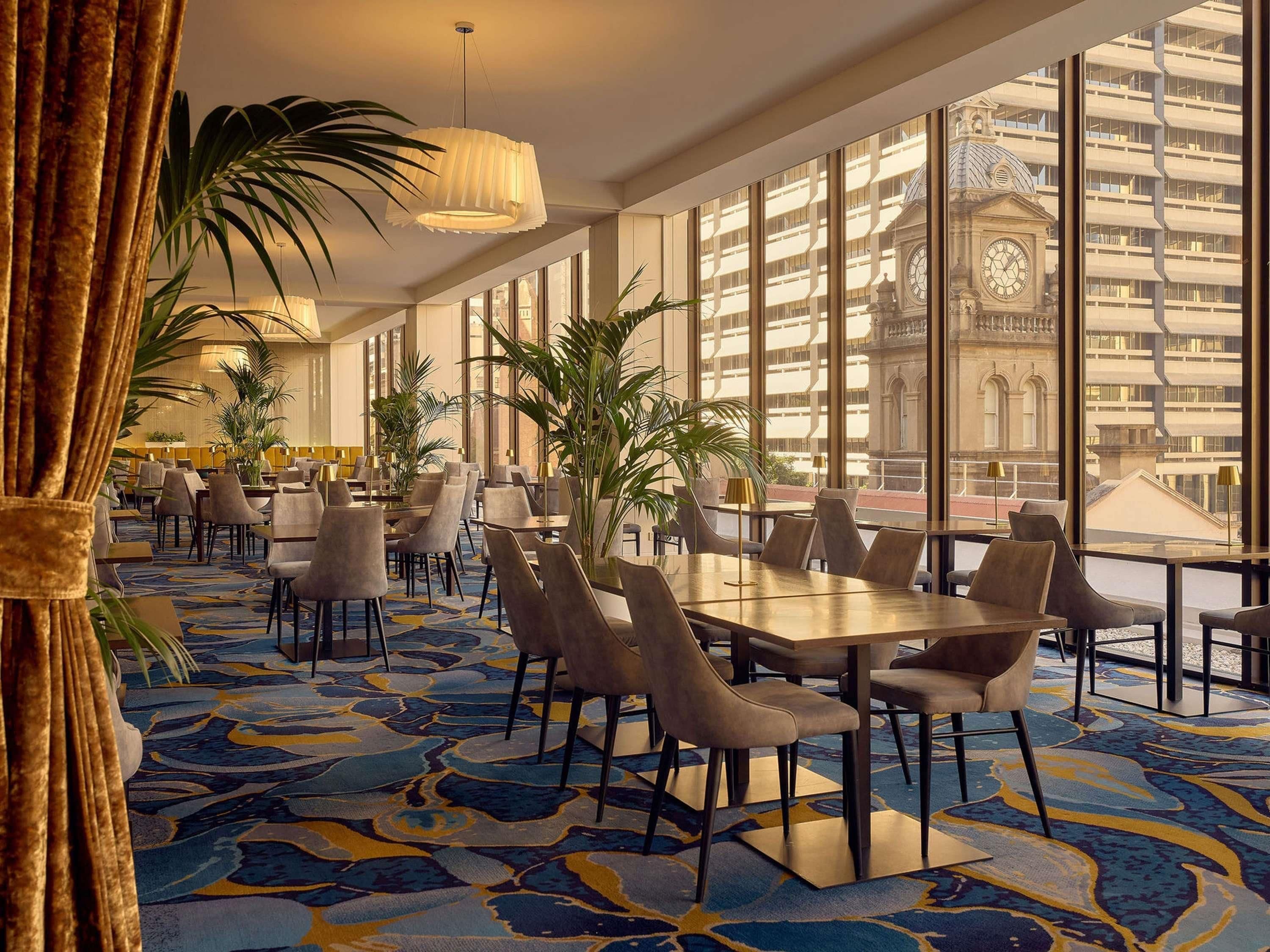 A hotel lobby with large windows, a patterned carpet, and modern furniture.