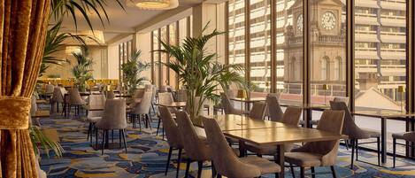 A hotel lobby with large windows, a patterned carpet, and modern furniture.