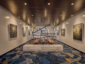 A hallway with artwork on the walls, a central bench, and a patterned carpet. - Sofitel Brisbane Central (Brisbane)