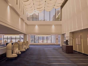 A spacious hotel lobby with a high ceiling, large windows, and a seating area with chairs and tables. - Sofitel Brisbane Central (Brisbane)