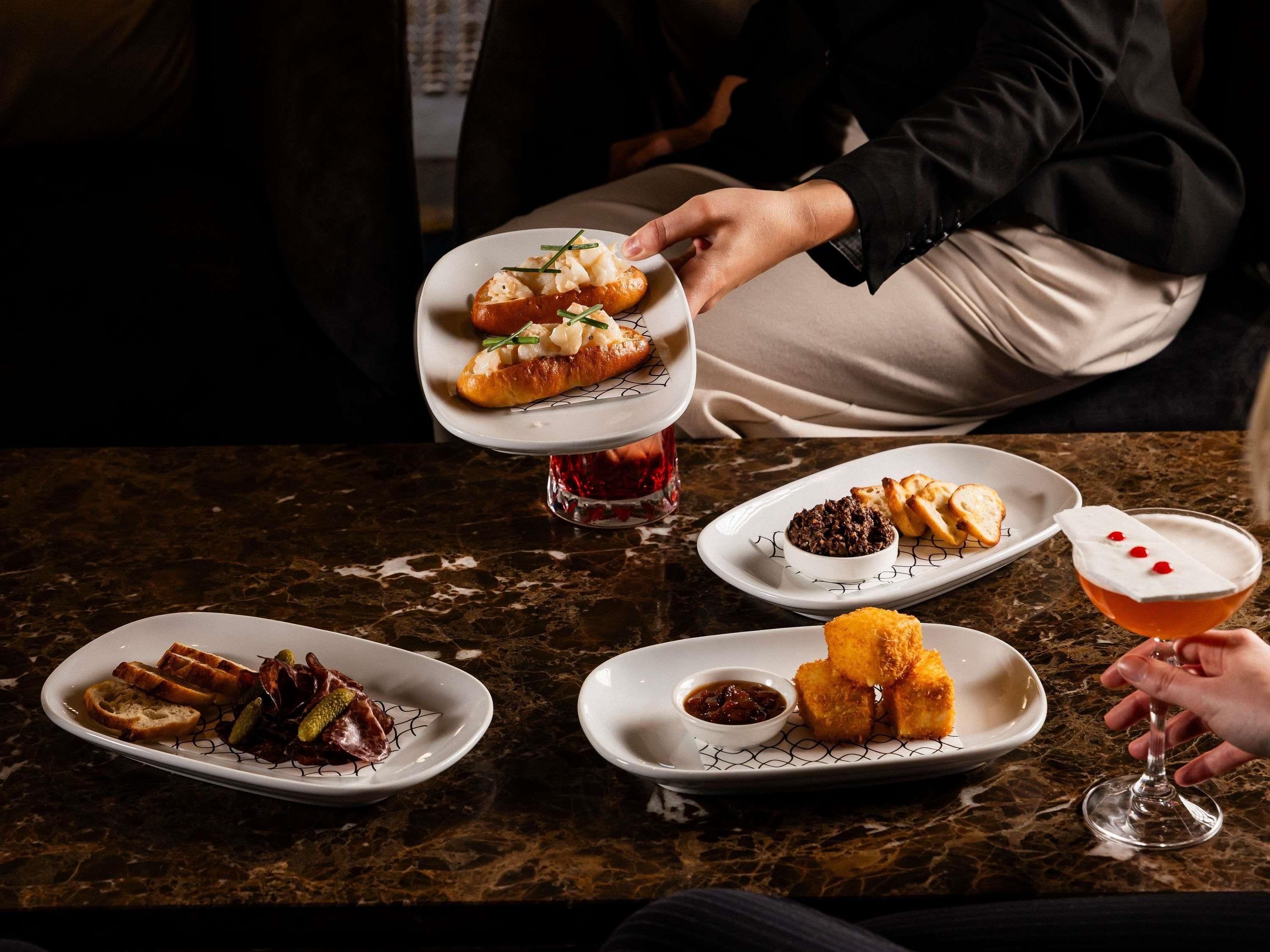 A dining table with various dishes, including seafood, bread, and a cocktail.
