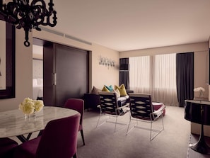A hotel room with a dining area, a sofa set, a TV, and a large window with curtains. - Sofitel Brisbane Central (Brisbane)