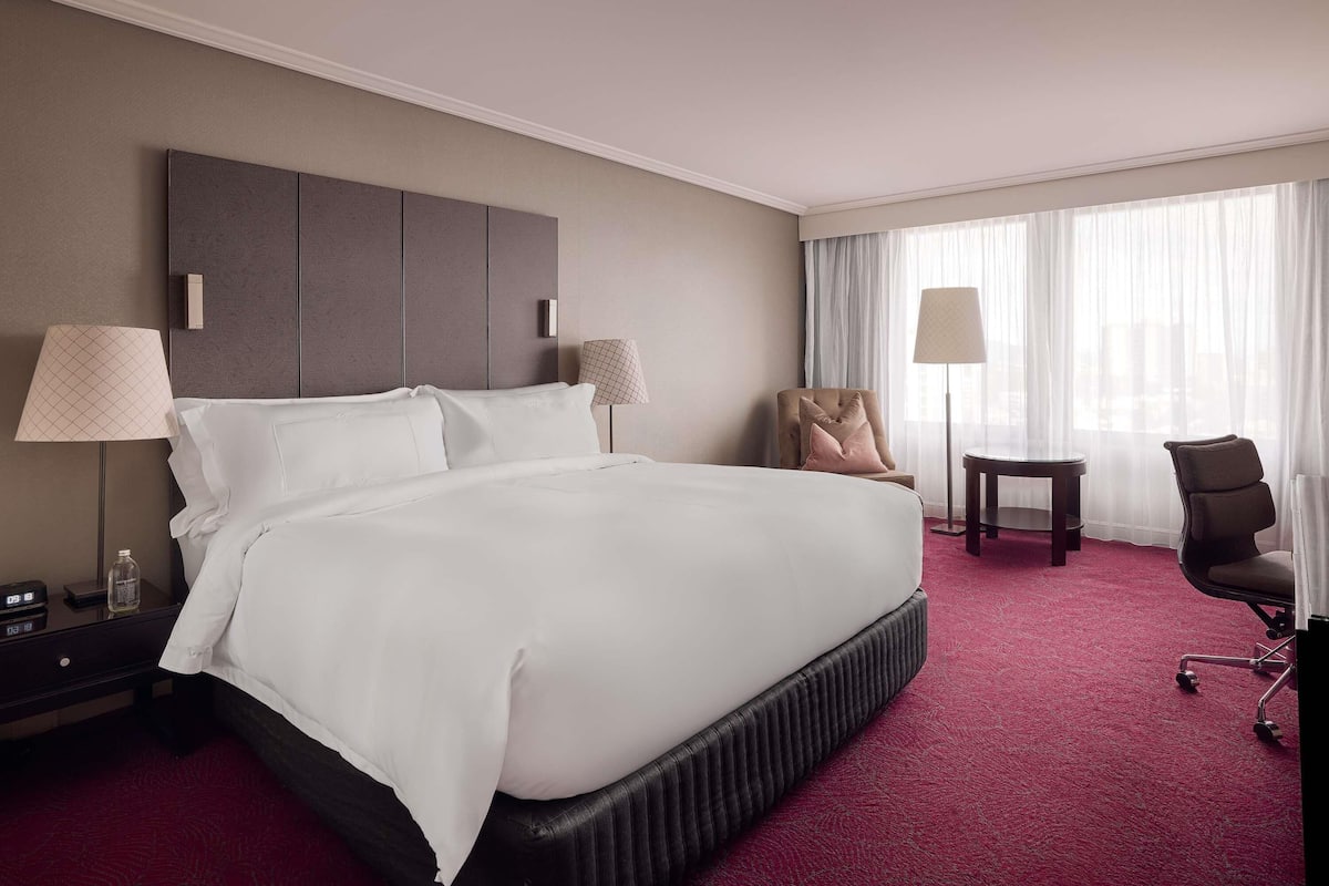 A hotel room with a large bed, bedside tables, a desk, and a chair.