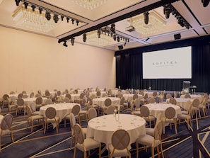 A conference room with round tables, chairs, a stage, and a large screen. - Sofitel Brisbane Central (Brisbane)