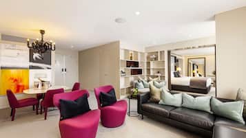 A modern living room with a sofa, chairs, a dining table, and a bookshelf.