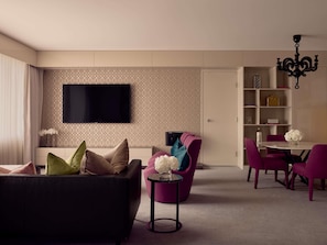 A modern living room with a black sofa, a purple armchair, and a dining area with a table and chairs. - Sofitel Brisbane Central (Brisbane)