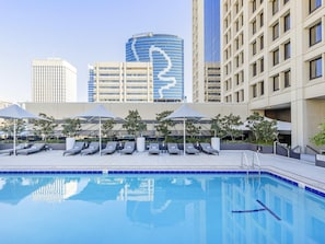A swimming pool with lounge chairs and umbrellas, surrounded by buildings. - Sofitel Brisbane Central (Brisbane)