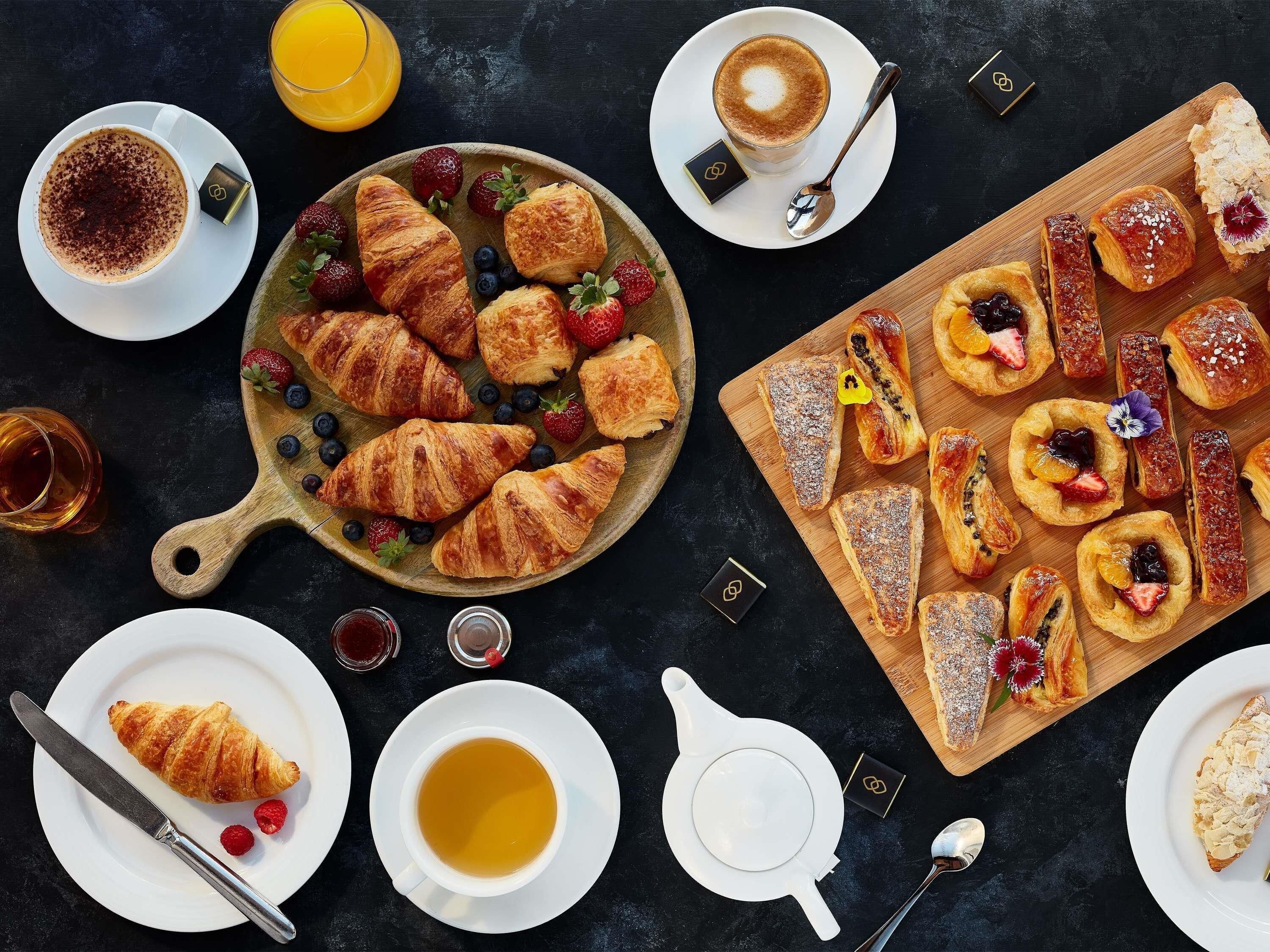 A breakfast setting with croissants, pastries, coffee, and juice.