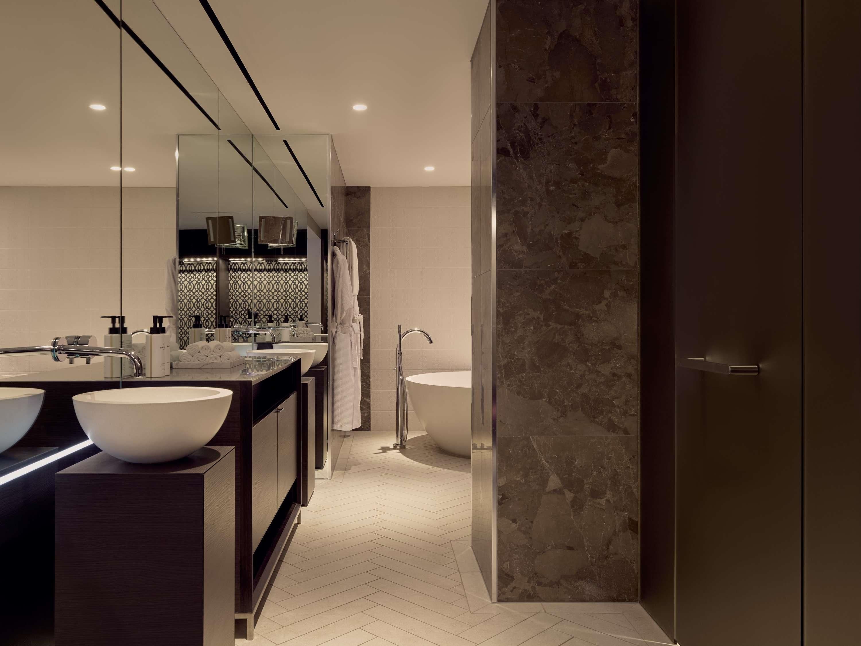 Une salle de bain moderne avec deux lavabos, un grand miroir et une douche à l’italienne.