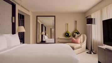 A hotel room with a large bed, a chair, a TV, and a mirror.