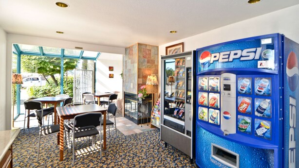 Ein Zimmer mit Essbereich, einer großen Pepsi-Getränkeautomaten und Blick durch eine Glastür.