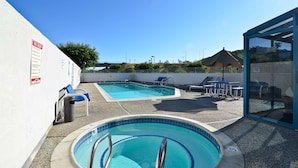 Ein Poolbereich mit zwei Pools, Liegestühlen und einer gläsernen Struktur.