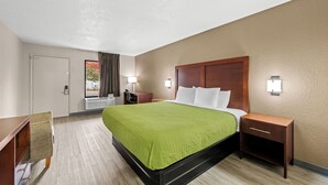 A hotel room with a bed, bedside tables, a desk, and a window with curtains. - Econo Lodge Kannapolis - Concord (Kannapolis)