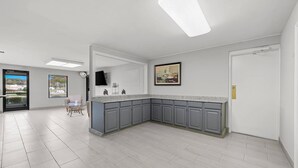 A modern kitchen with grey cabinets, a granite countertop, and a built-in oven. There is a dining area with a table and chairs, and a large window offering a view of the outdoors. - Econo Lodge Kannapolis - Concord (Kannapolis)