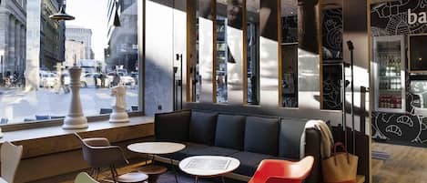 Un interior moderno con un amplio ventanal, una zona de estar con sofá y sillones, y una barra con refrigerador.