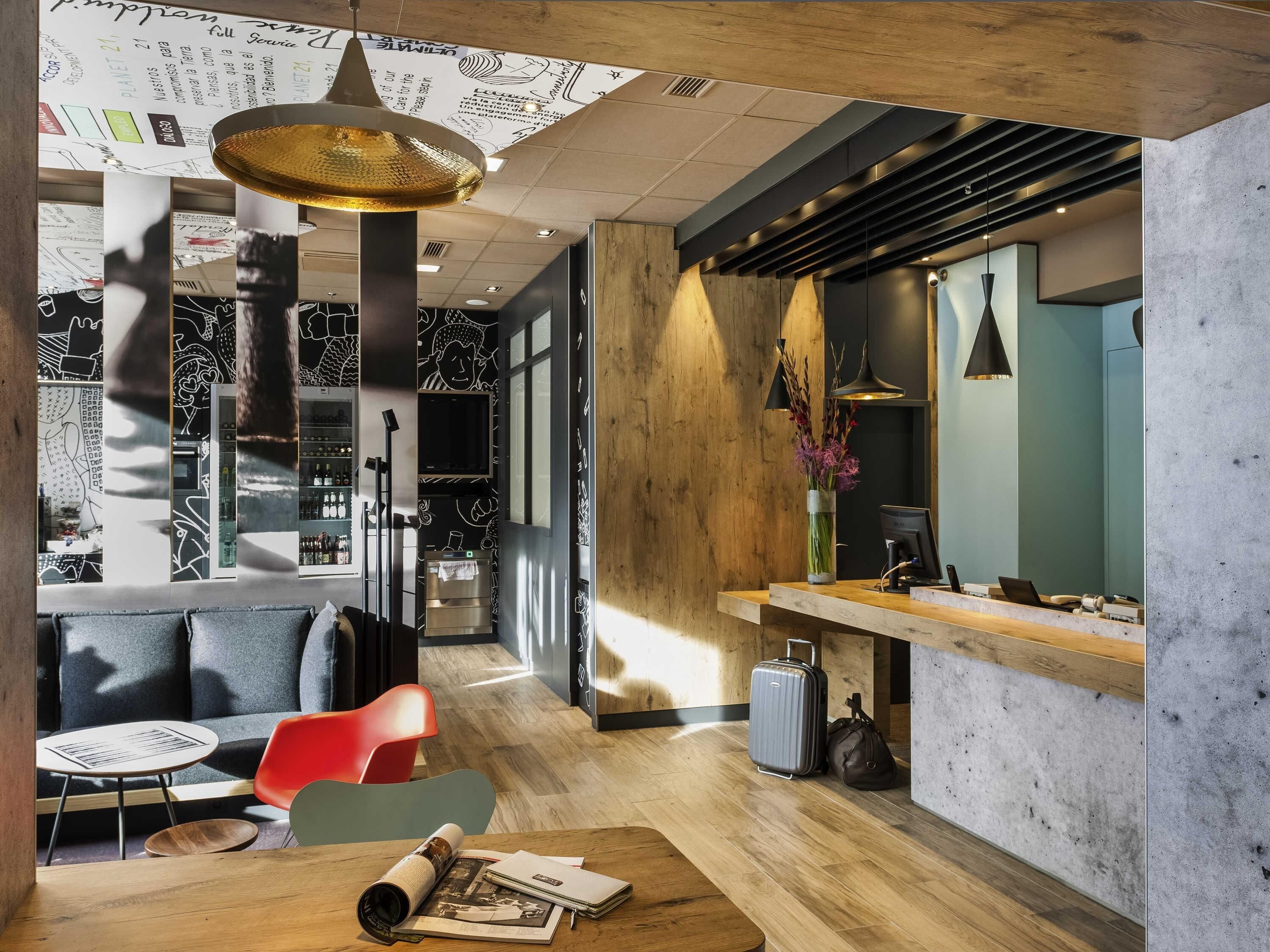 A modern interior with a wooden floor, a bar area, and a seating area with a red chair.