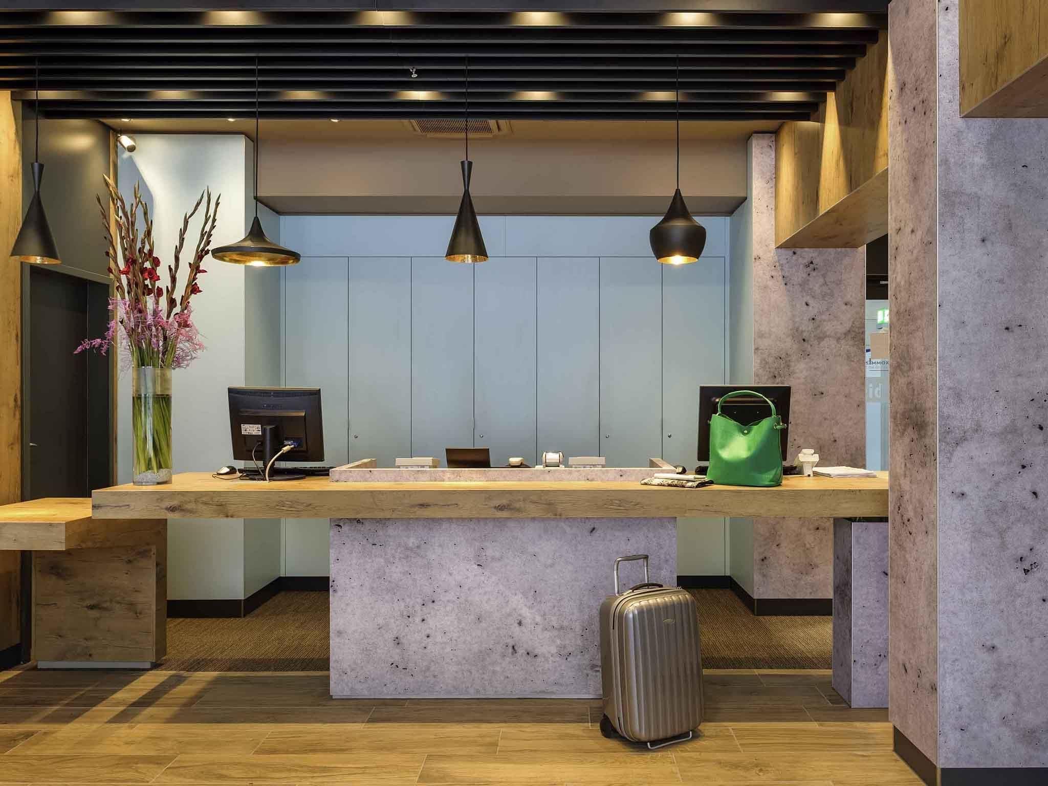 Un mostrador de recepción con una computadora, una bolsa verde y una maleta.