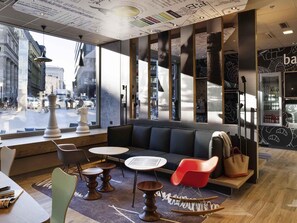 A modern interior with a large window, a seating area with a sofa and chairs, and a bar area with a refrigerator.
