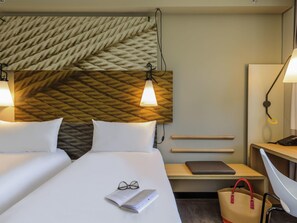 A hotel room with a bed, bedside lamps, a nightstand, a desk, a chair, and a wall with a textured pattern. - ibis Hotel Köln Am Dom (Cologne)