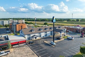 Stylish building with a mix of architectural styles, set amidst lush greenery and a spacious parking lot.