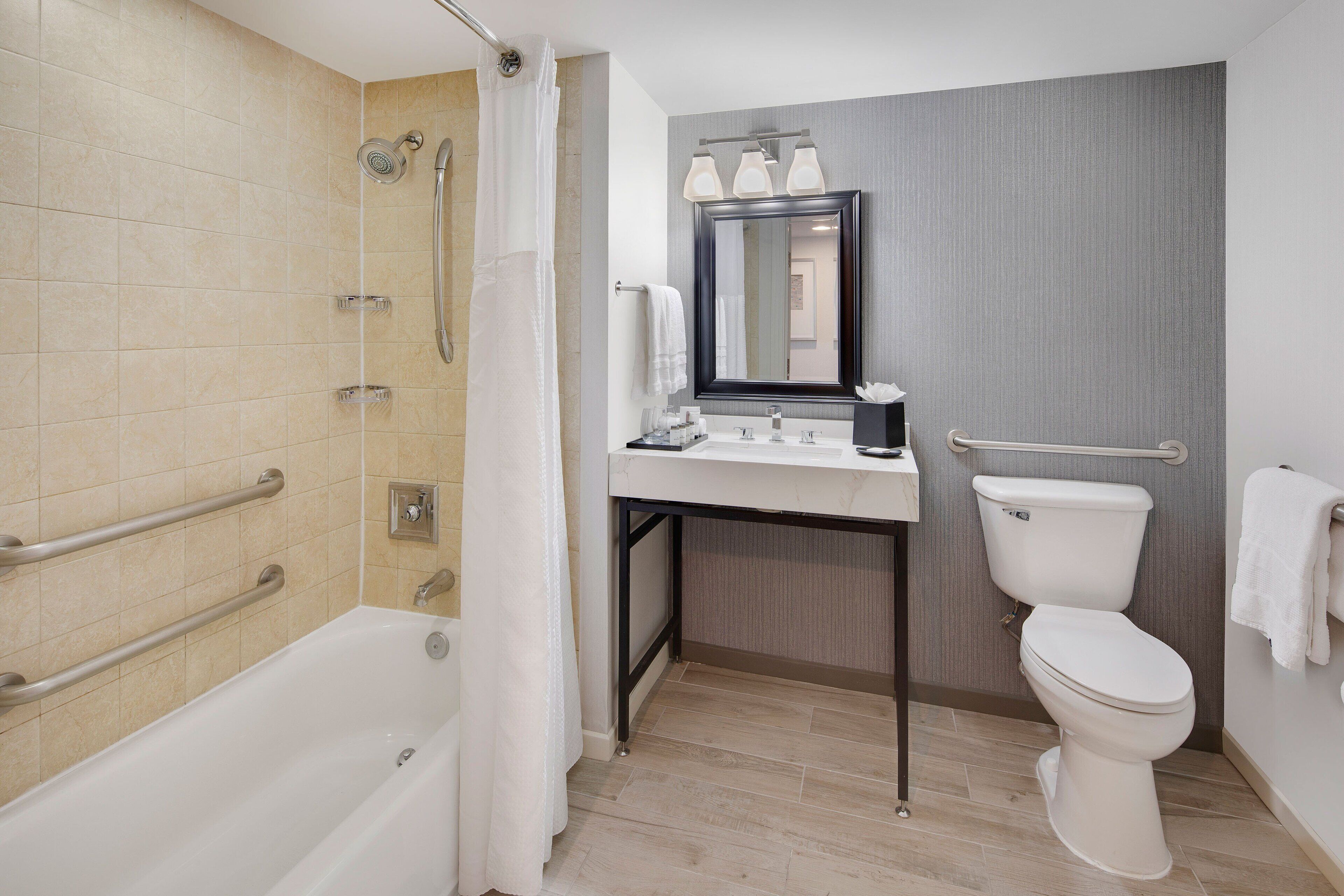 A modern bathroom with a bathtub, shower, toilet, and vanity.