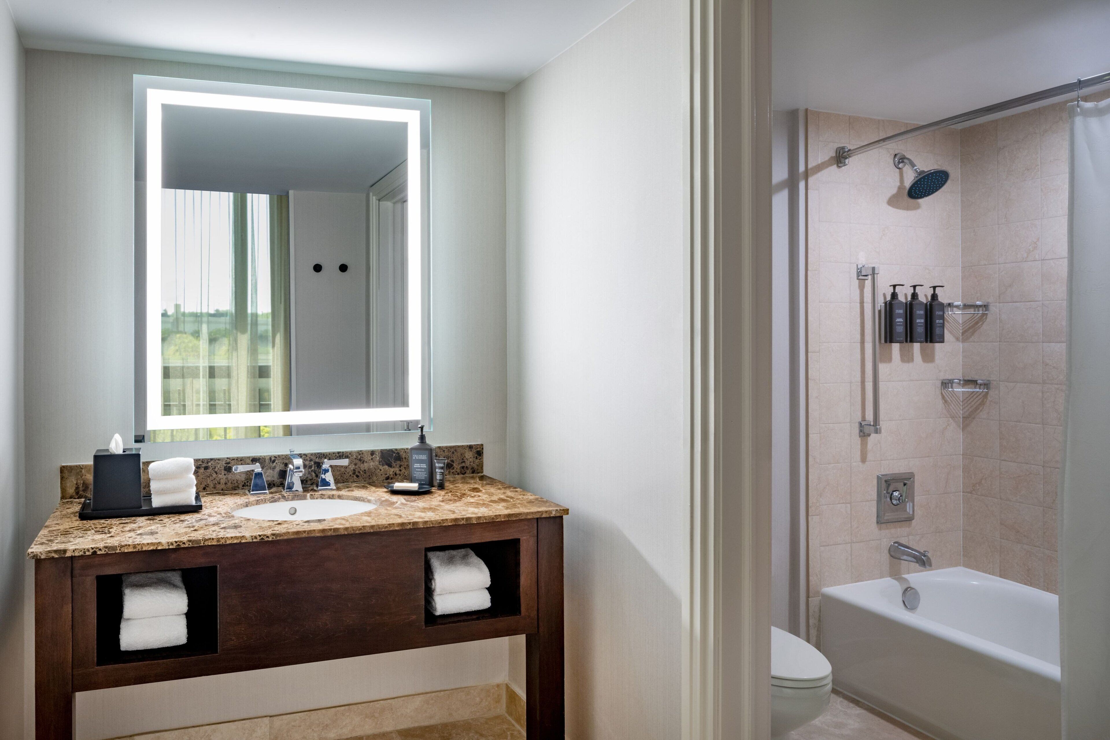 A modern bathroom with a granite countertop sink, a large mirror, and a walk-in shower.