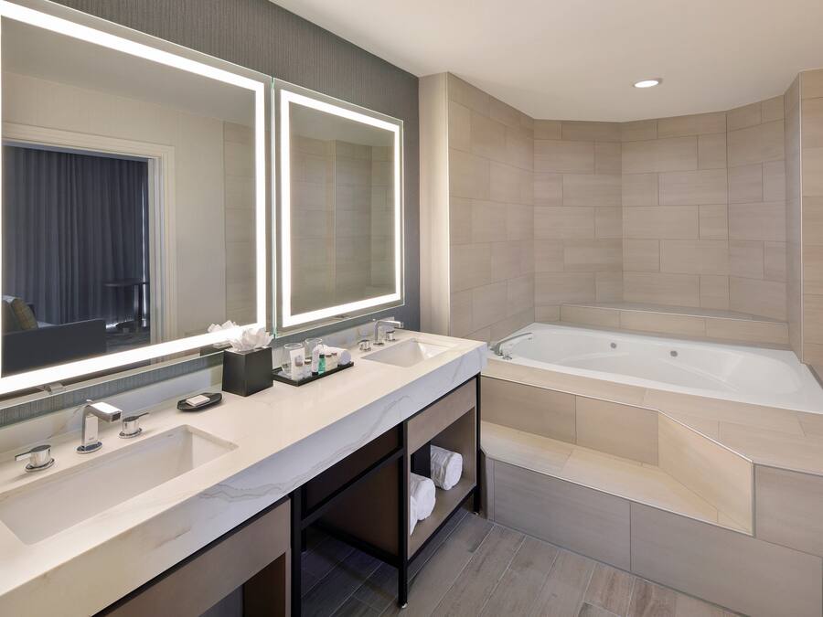 A modern bathroom with dual sinks, a large mirror, and a separate bathtub.