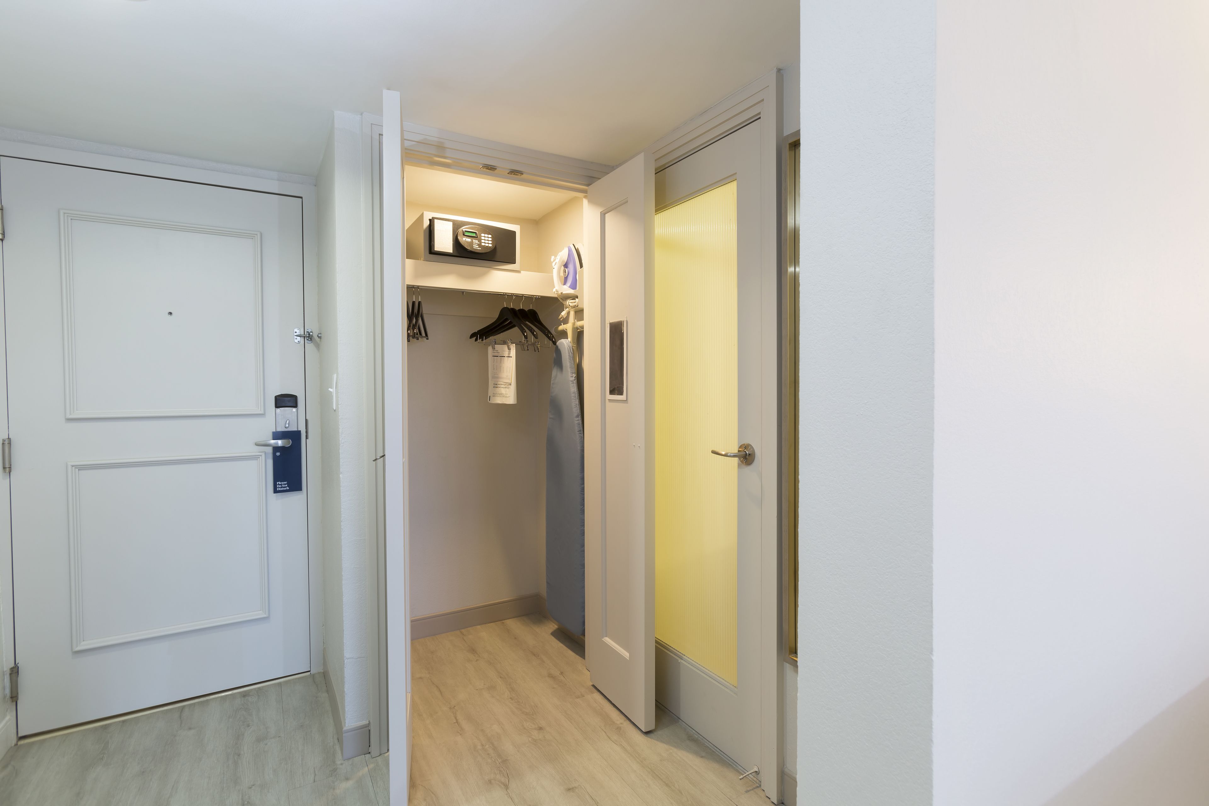 A hallway with a white door, a microwave, and a coat rack.