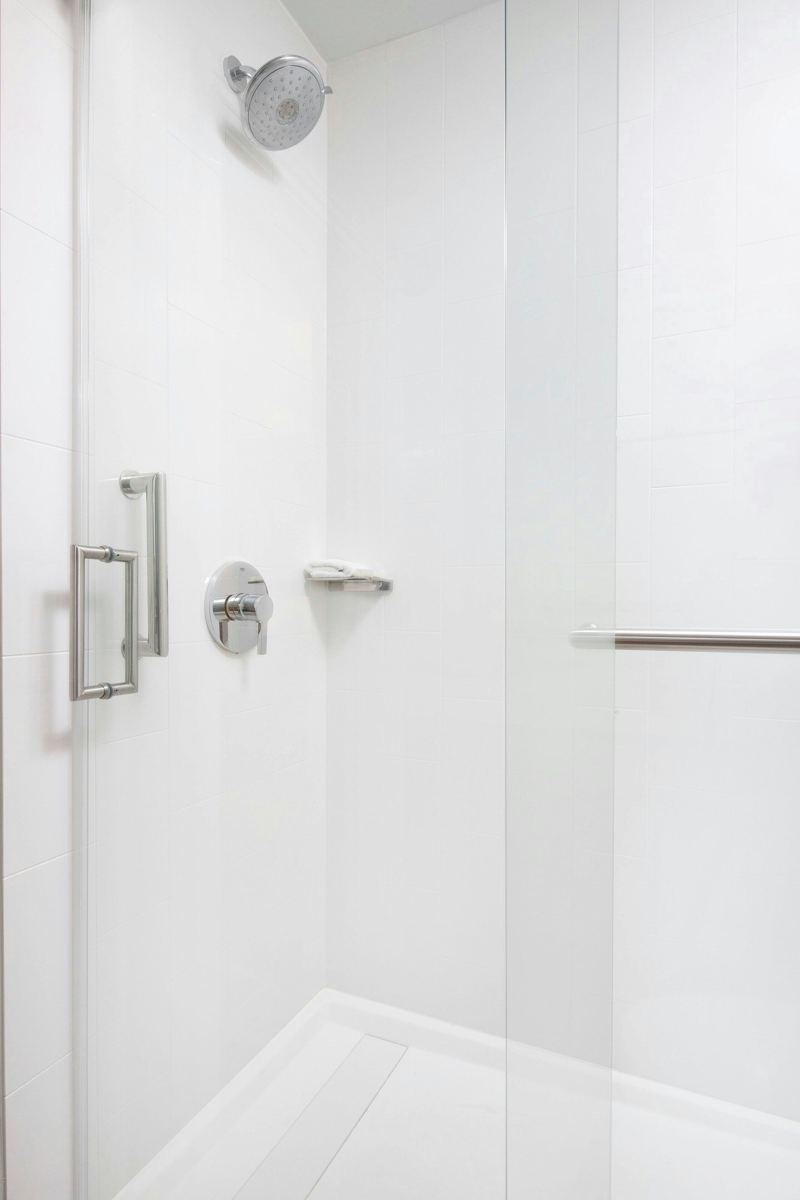 A modern shower with a handheld showerhead, a wall-mounted faucet, and a glass-enclosed shower stall.